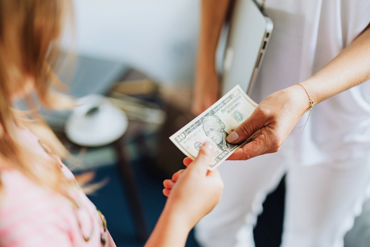 Child receiving money from parent, showing how kids earn money while saving for a toy.