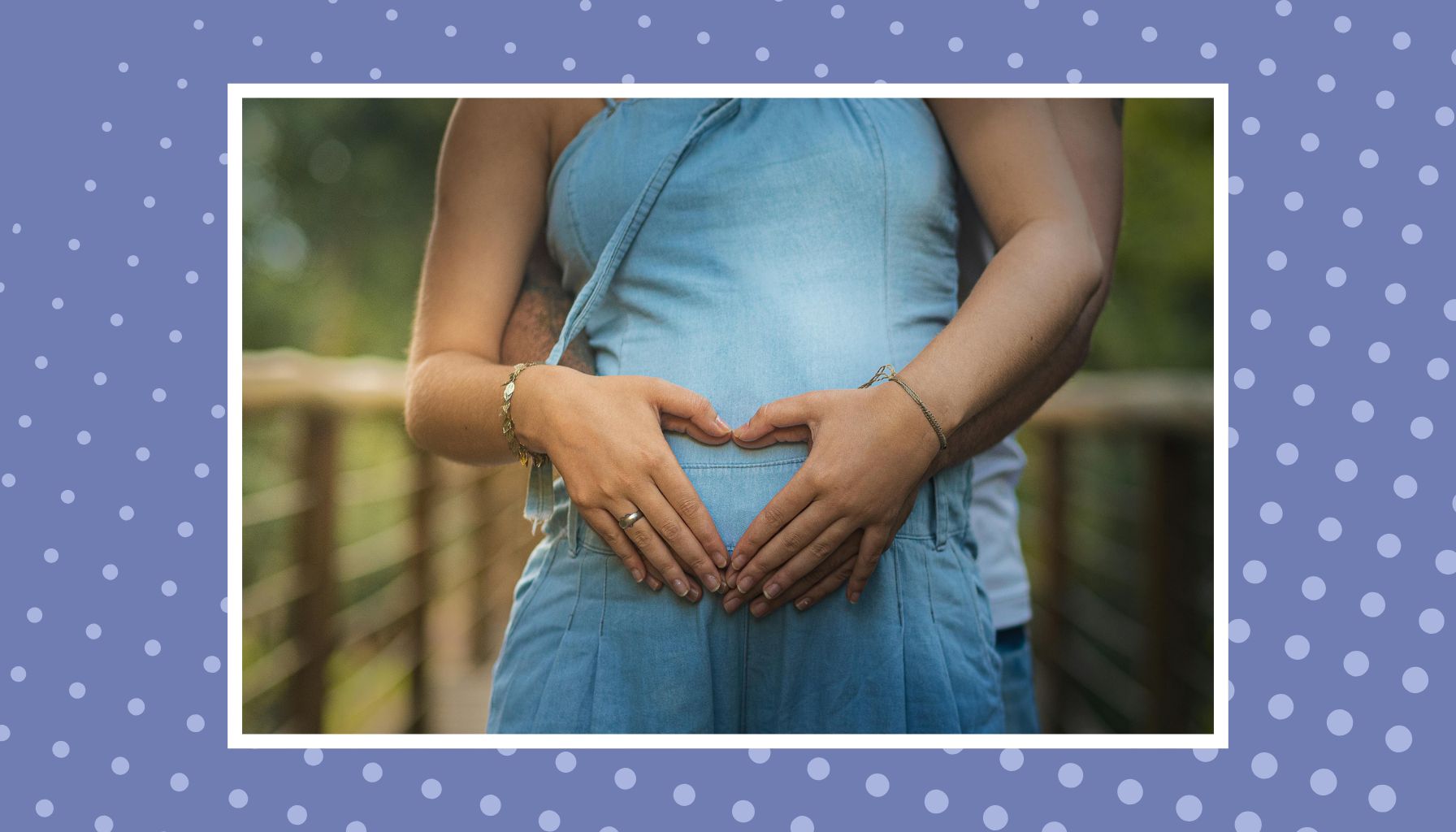 Pregnant woman holding her baby bump with hands forming a heart during pregnancy.