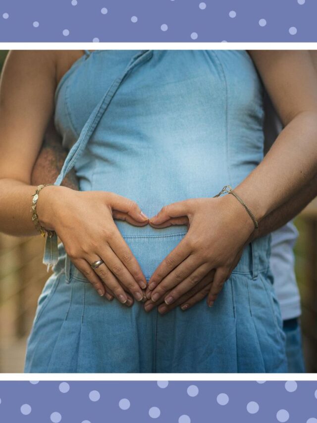 Pregnant woman holding her baby bump with hands forming a heart during pregnancy.