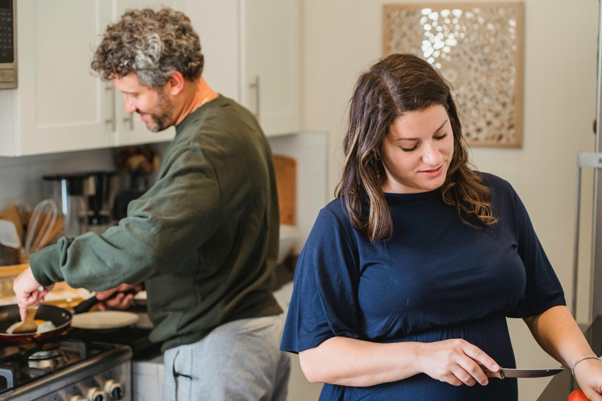 Couple preparing food together in the kitchen while managing different household tasks.