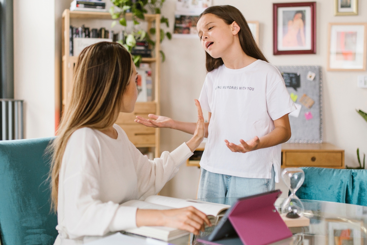 Mother calmly talking with her frustrated daughter during a stressful moment at home.