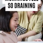 Mother sitting beside her daughter as she completes schoolwork at home.