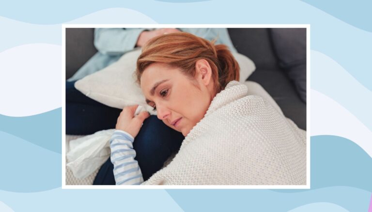 Tired mother resting on a couch under a blanket while feeling overwhelmed by the mental load of parenting.